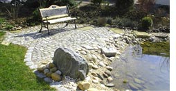 Granitpflaster mit Sitzgelegenheit am Teich